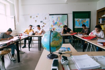Unterricht im Kurs BAJU: Kursteilnehmer*innen sitzen lesend an ihren Tischen