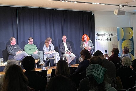 Podium mit vier sitzenden Personen bei einem Podiumsgespräch in der Hauptbücherei