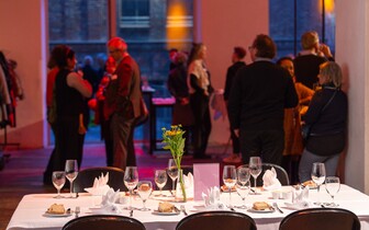 gedeckter Tisch mit Publikum im Hintergrund bei der Veranstaltung Demokratie am Tisch
