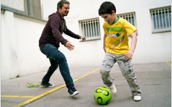 freiwilliger Mitarbeiter spielt Fußball mit Jungem