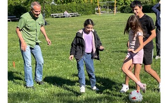 Freiwillige Mitarbeiter*innen im Park beim Fußball spielen mit geflüchteten Kindern